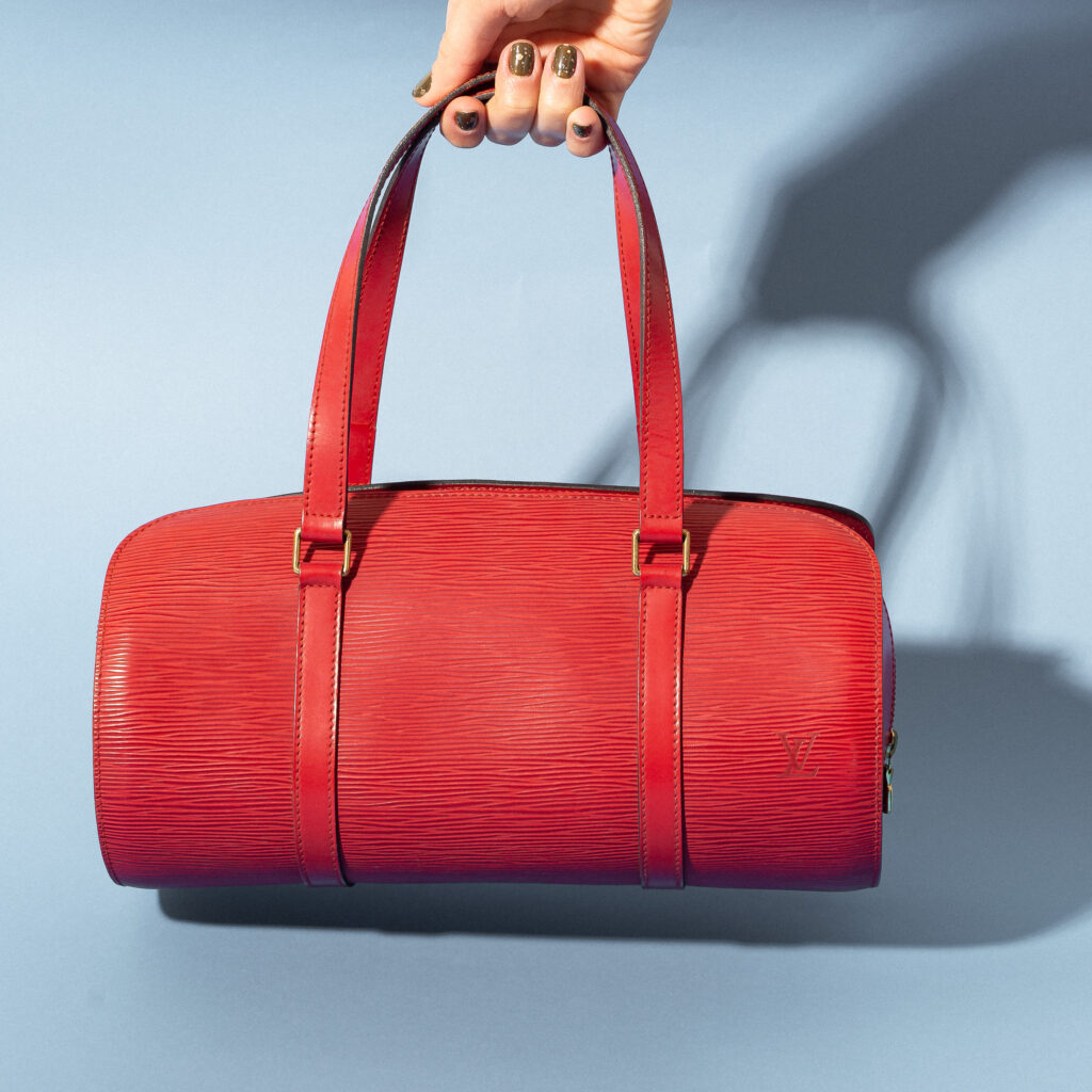 Bolsa da marca Louis Vuitton, tamanho 30 cm C x 15 cm A. Confecionada em couro epi vermelho. A bolsa conta com duas alças de mão, um bolso interno e fecho por meio de zíper. Encontra-se em ótimo estado de conservação, com leves desgastes e manchas de caneta no forro de dentro.