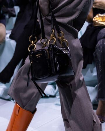 Modelo utilizando uma bolsa de marca, mostrando o que combina com calça da prada.