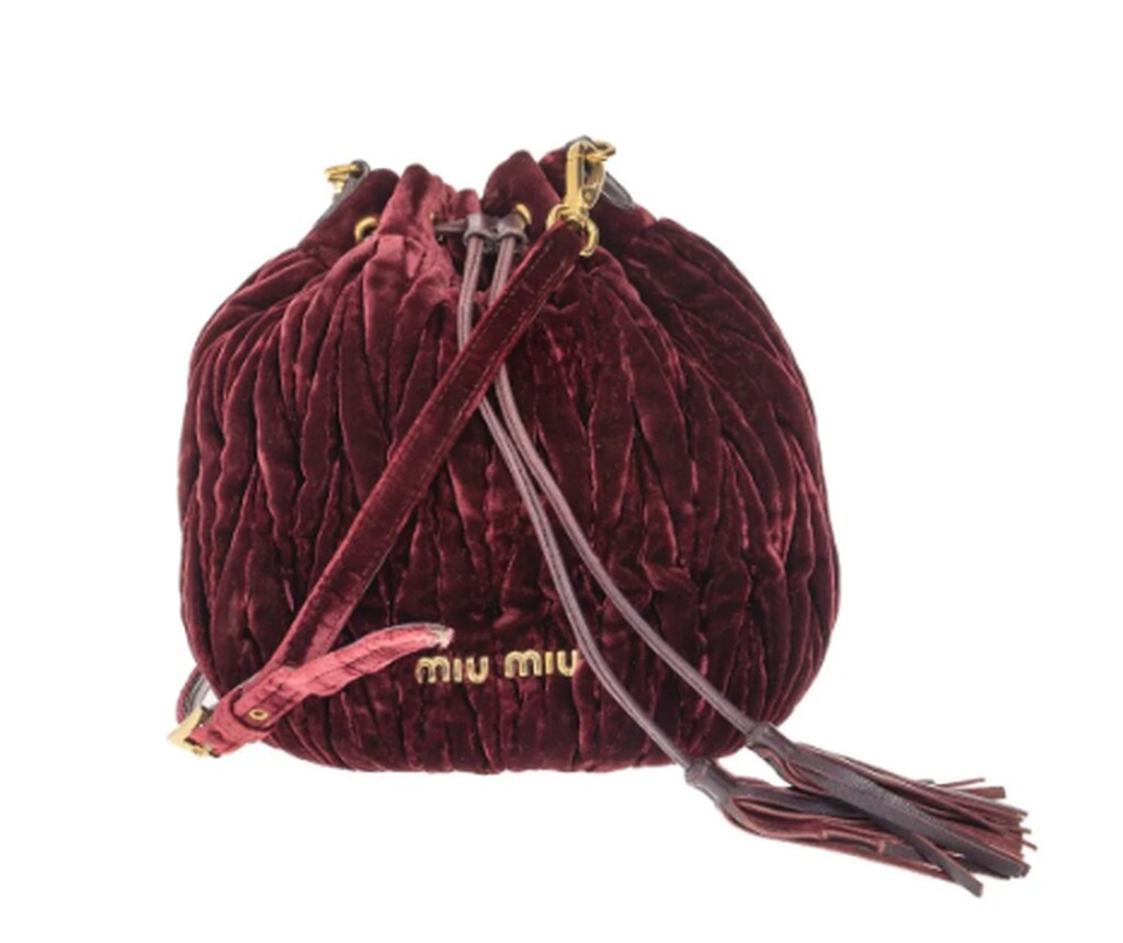 Bolsas do momento: bolsa Miu Miu bucket em veludo bordô matelassê com alça transversal e detalhe de tassel.