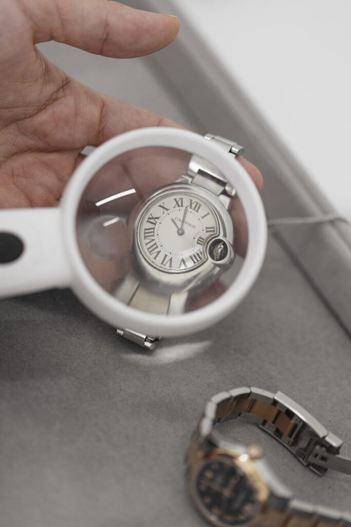 Relógio Cartier em destaque sob lupa, símbolo de precisão e luxo, representando marcas mais caras de relógio, com detalhes refinados e elegantes atemporais em cada componente.