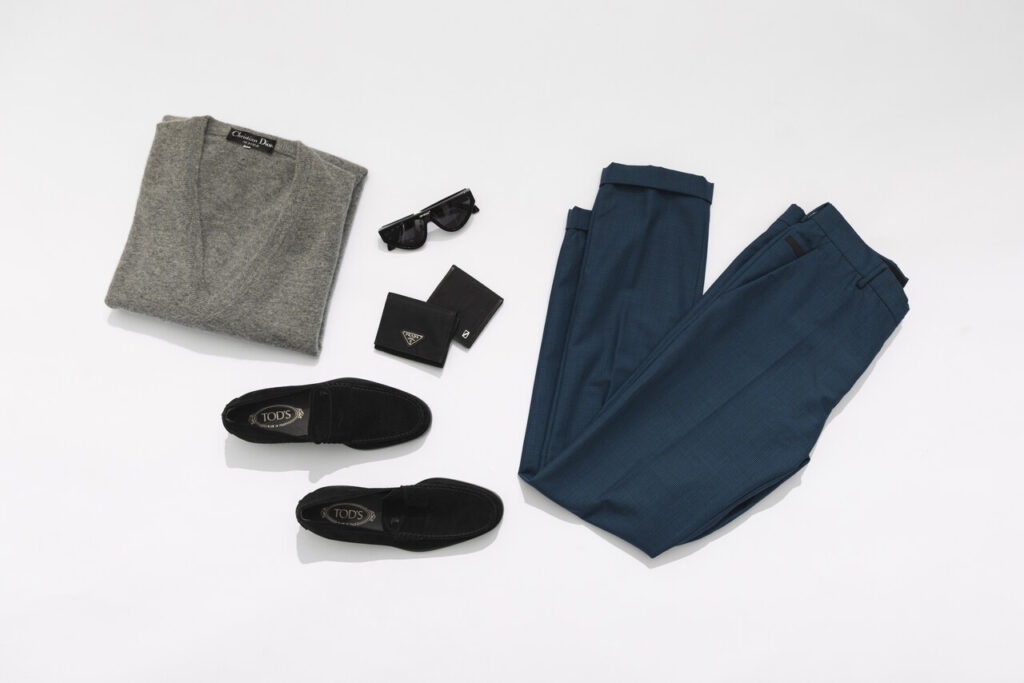 Look sofisticado com suéter Dior, calça azul, loafers Tod’s e acessórios Prada, destacando moda masculina 2026 em estilo elegante coordenado.