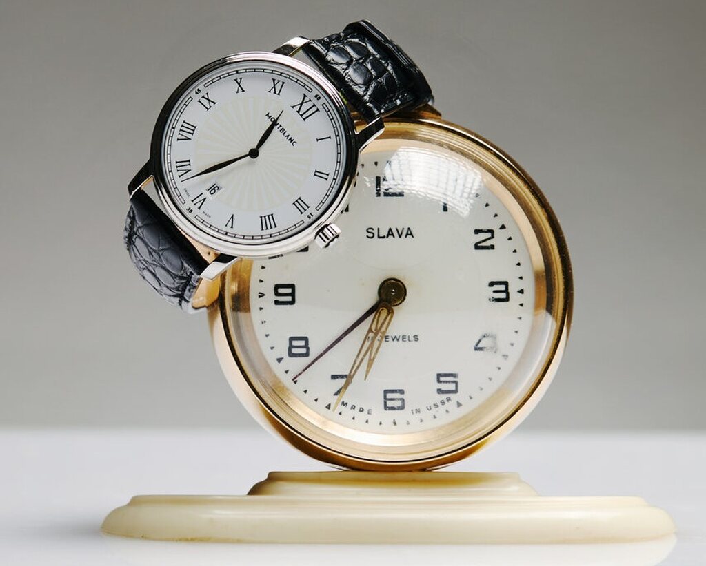 Relógio de pulso com numerais romanos e relógio de mesa dourado, contraste histórico perfeito como presente para Dia dos Pais de luxo.